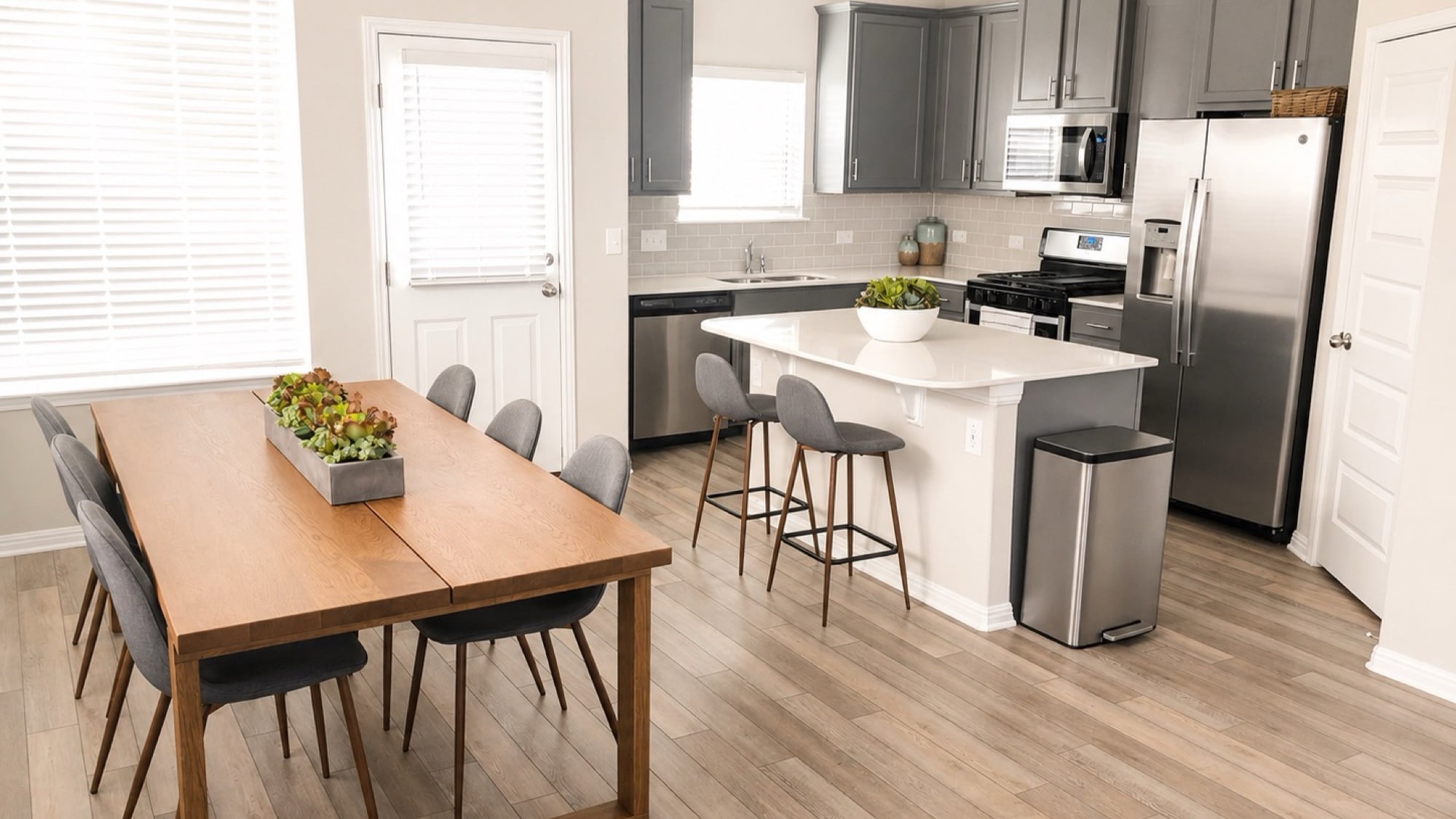 The open kitchen and dining area at Mary Lewis, with a wooden table, a kitchen island with stools, and stainless steel appliances
